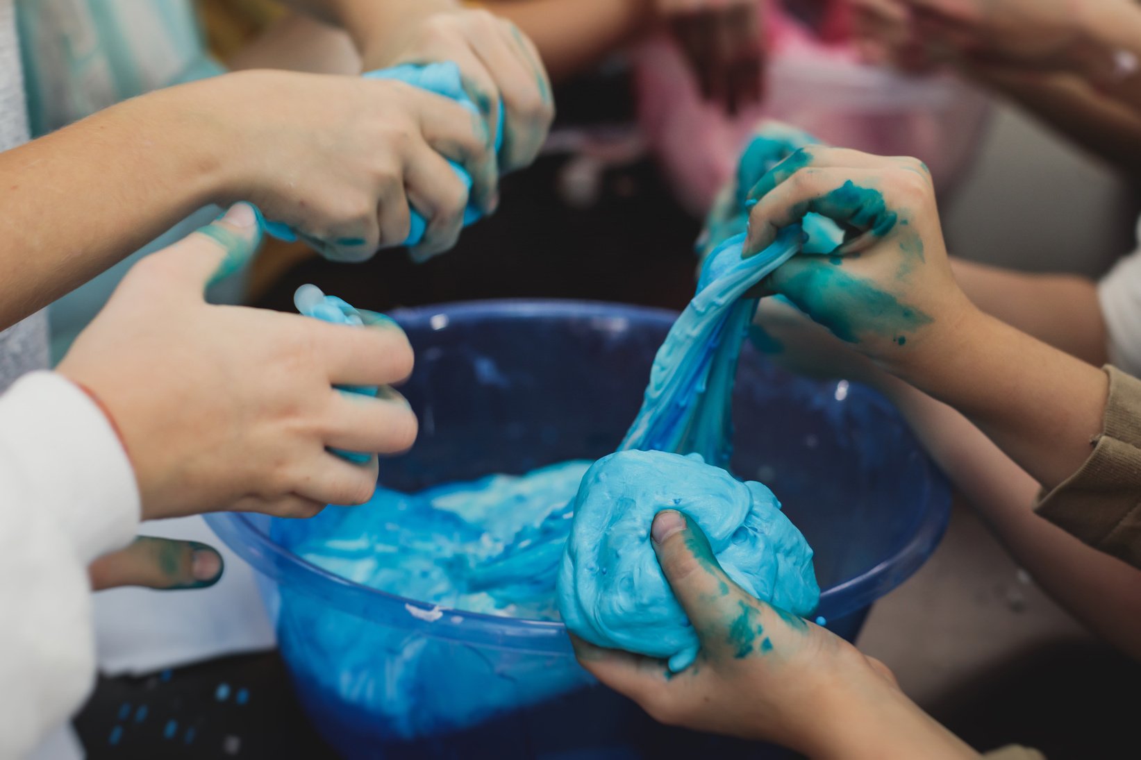 Group of kids making a multicoloured slime, pink, blue and white slime toy on kids birthday party, kid playing with slime, homemade slime